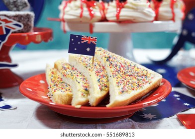 Australian theme party table with flags and iconic food including mini pavlovas, lamingtons, meat pies and fairy bread.                          