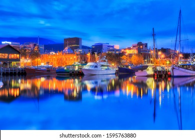 Australia's smallest state Tasmania capital city Hobart. Sullivan's cove at sunset illuminated buildings gallery and docked yachts with lights.