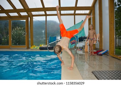 Niederösterreich, Austria - August, 2018: Boy Plunges Head First Into An Indoor Swimming Pool By Handstand, Doing A Cartwheel.