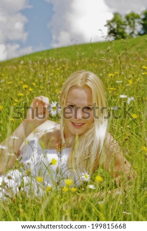 Austria, Salzburger Land, Altenmarkt, Young woman in meadow holding flower, smiling, portrait