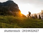 Austria- tyrol- hiker with backpack hiking in meadow at sunset