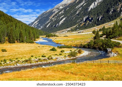 Austrian Alps. Rushing stream of melted azure water flows into the Krimml Falls valley. Mountains covered with evergreen forest. - Powered by Shutterstock