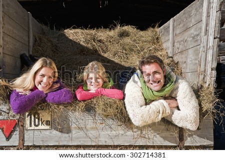 Austria,Salzburg,Flachau,Family lying in hay trailer