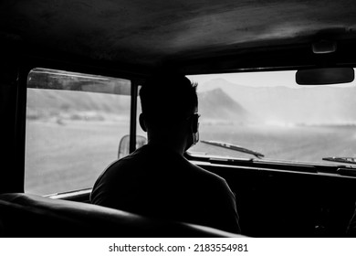 authentic another side view through the mountains by riding a jeep and visitors sitting in it and the bottom view of the mountain with sand and air in the jeep - black and white