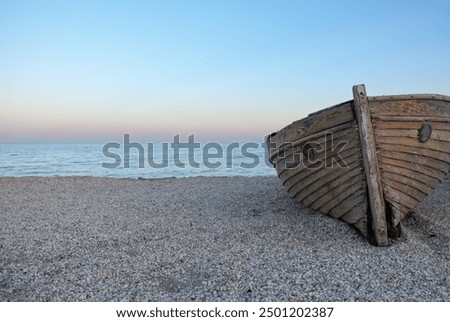 Authentic beach for swimming. Damaged old fishing boat on the beach full of seashells. Boat stranded on the island. Damaged boat on the beach. Sunset on the beach, red and blue colors on the horizon. 