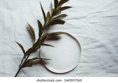Authentic ceramic table setting  mock up with linen napkin top view. Wedding holiday table setting mockup background for wallpaper, design, lettering, cards, blogs. Tableware with green branch.