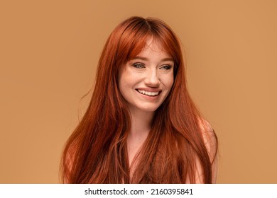 Authentic Cheerful Ginger Girl With Beautiful Smile, Natural Freckles, Long Hair And Fringe. Attractive Red Head Woman Posing In Studio. A Lot Of Copy Space. 
