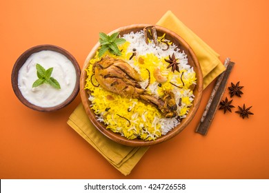 Authentic Chicken Biryani served in a bowl or plate over colourful or wooden background. It's a delicious recipe of Basmati rice mixed with spicy marinated chicken served with salad. Selective focus