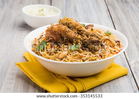 Authentic Chicken Biryani served in a bowl or plate over colourful or wooden background. It's a delicious recipe of Basmati rice mixed with spicy marinated chicken served with salad. Selective focus