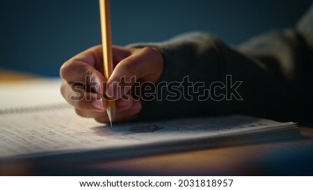 Authentic Close Up Shot of a Young Person Writing with Pencil in Notebook. Teenager Making Homework for School. Education Concept.