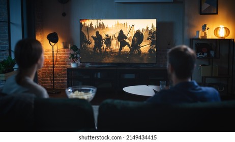 Authentic Couple Spending Time at Home, Sitting on a Couch and Watching Latest Blockbuster on Flat Screen Television Set. Man and Woman Streaming Movie or Show Using Home Cinema System. - Shutterstock ID 2149434415