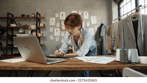 Authentic female clothing designer is working in her office, redrawing sketches on graphics tablet for her new collection - fashion, art concept  - Powered by Shutterstock