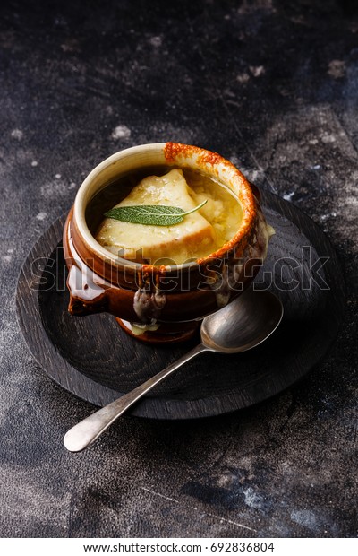 Authentic French Onion soup
with dried bread and cheddar cheese in bowl on dark background copy
space