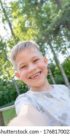 Authentic Funny Small Boy Taking Selfies And Laughing. Smiling Cute Boy Taking Photos And Facetime Chatting With Family. Vertical Photo.