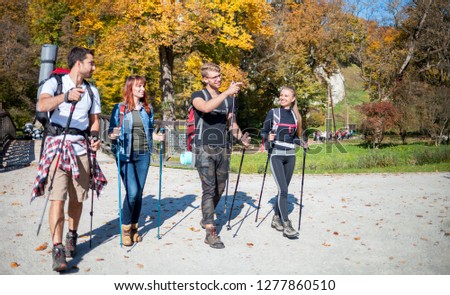 Authentic group of friends on tourist trip walking with backpacks and trekking sticks