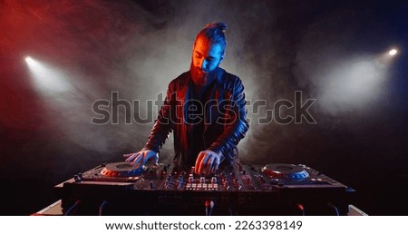 Authentic hipster dj rocking the party up. Bearded disc jockey working in a nightclub, composing a dance music list, spotted by red and blue lights - nightlife concept  Сток-фото © 