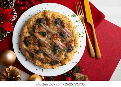 Authentic Italian focaccia with salted anchovies, sun-dried tomatoes, and black olives. Top view table with christmas decorations.