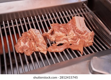     An authentic korean barbecue dining experience unfolds over a heated metal grill. Marinated pork ribs sizzle to perfection capturing the essence of traditional culinary execution and genuine local gastronomy. A fresh lettuce leaf cradles the roasted meat paired with savory dipping sauce and garlic showcasing classic flavor profiles. This mouthwatering setup provides exceptional visual context for regional food documentaries recipe publishing or restaurant menu designs. It highlights the enduring charm of communal table cooking appealing to global audiences seeking real asian culinary adventures.                           