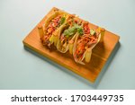 Authentic mexican chicken and beef tacos. Three tacos served on a wooden board over pastel blue mint background. Traditional mexian food, delicious dish. Copy space banner.