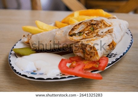 Authentic Middle Eastern shawarma wrap served with creamy garlic sauce, French fries and tomato.