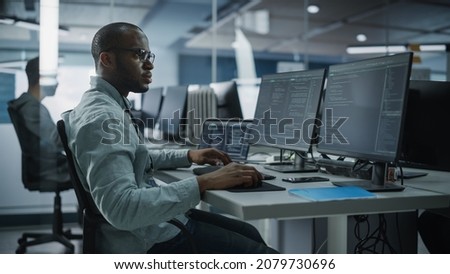 Authentic Office: Professional Black IT Programmer Working on Desktop Computer. Male Website Developer and Software Engineer Developing App, Video Game. Terminal with Coding Programming Language