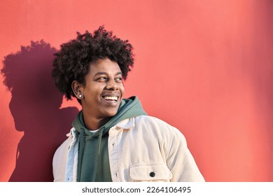 Authentic photo of young happy African American cool hipster teen guy face laughing on red city wall lit with sunlight. Smiling cool rebel gen z teenager model looking away at advertising copy space. - Powered by Shutterstock