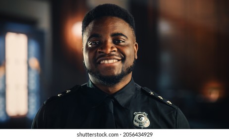 Authentic Portrait Of Happy And Handsome Black Policeman In Universal Uniform Smiling At Camera. Successful African American Law Enforcement Agent. Courtroom Security Guard At Work.