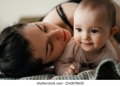 Authentic Portrait Of A Little Girl Hugging Mom. Weekdays Of An Ordinary Family Where A Mother Takes Care Of A Little Daughter