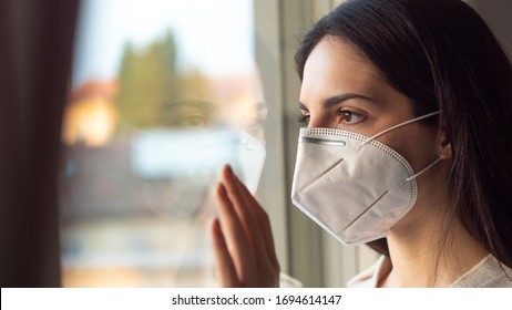 Authentic Portrait Of An Young Woman Wearing A Protective Mask Is Looking Through A Window. Concept Of Pollution, Environment, Protection, Virus Transmission, Breathing,safety, Quarantine, Covid-19