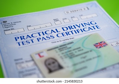 Authentic Practical Driving Test Certificate which is received after passing driving test in the UK and blurred provisional driving licence. Stafford, United Kingdom, April 13, 2022.