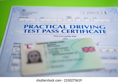 Authentic Practical Driving Test Certificate which is received after passing driving test in the UK and blurred provisional driving licence. Stafford, United Kingdom, April 13, 2022.