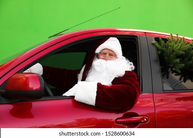 Authentic Santa Claus with fir tree driving car against green background - Powered by Shutterstock