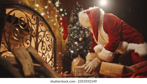 Authentic santa clause leaving christmas gifts near fireplace and christmas tree - chritmas spirit, traditions, holidays and celebrations concept 