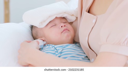 authentic shot of asian baby has fever and his mother checks temperature by thermometer on sofa in close up - Shutterstock ID 2102231185
