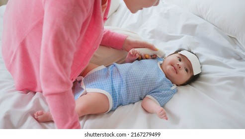 authentic shot of asian baby has fever and his mother checks body temperature by thermometer on bed - Shutterstock ID 2167279499