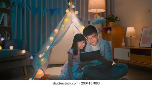 authentic shot of asian girl and her father enjoy their fun time with digital tablet in the evening at home - Powered by Shutterstock