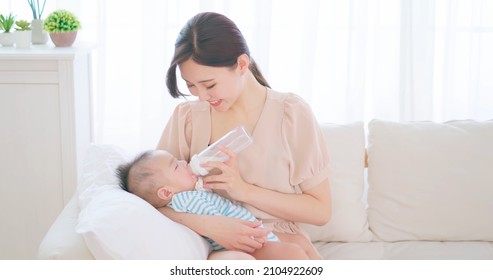authentic shot of asian mother feeds her baby from bottle and she feels happiness