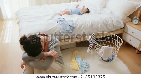 authentic shot of asian mother has postpartum depression with her baby who is lying on bed 