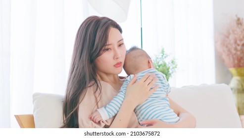 authentic shot of asian mother holding her crying baby on sofa has postpartum depression in close up - Powered by Shutterstock