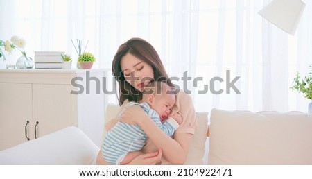 authentic shot of asian mother holding her crying baby on sofa has postpartum depression