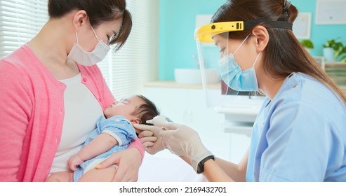 Authentic Shot Of Asian Mother And Infant In Pediatrics Clinic - Doctor Examine Crying Baby Health And Using Ear Thermometer To Check Body Temperature
