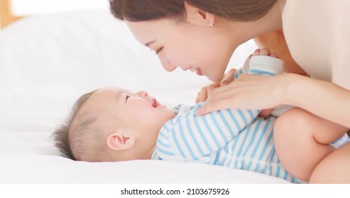 authentic shot of asian mother plays with her baby on the bed - Shutterstock ID 2103675926