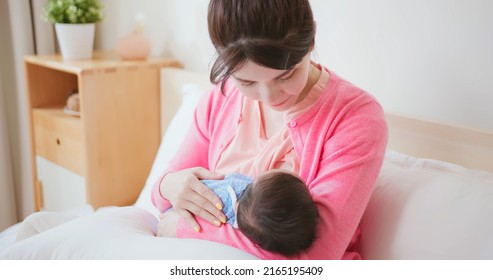 Authentic Shot Of Asian Mother Sitting On Bed Is Breastfeeding Her Baby