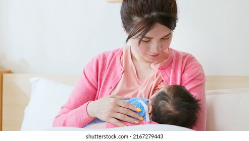 Authentic Shot Of Asian Mother Sitting On Bed Is Breastfeeding Her Baby