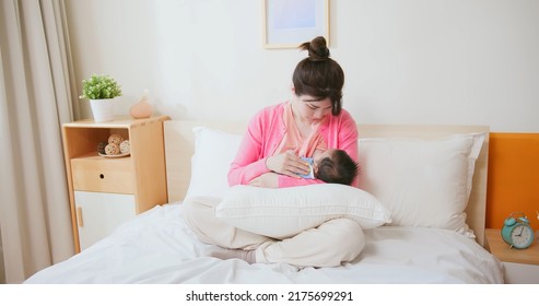 Authentic Shot Of Asian Mother Sitting On Bed Is Breastfeeding Her Baby