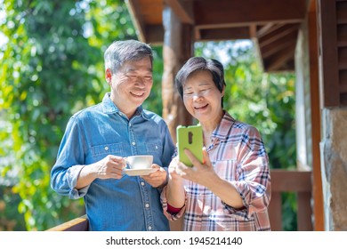 Authentic Shot Of Asian Senior Retired Couple Watching Content On Social Media Networks Or Their Photos Together While They Are Traveling