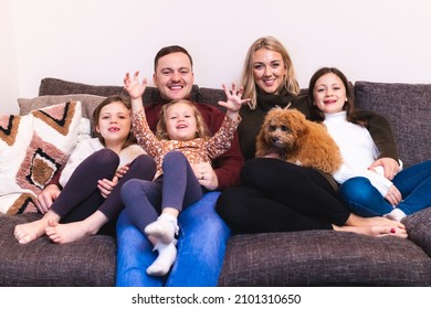 Authentic Shot Of Happy Family Together At Home On The Sofa With The Dog - Candid Beautiful Young Family With Children Enjoying Time Together - Lifestyle And Family Concepts