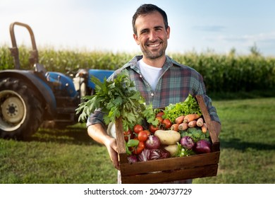 Authentic shot of happy farmer holding basket with fresh harvested at the moment vegetables and smiling in camera on countryside field. Concept:biological, bio products, bio ecology, vegetarian and vegan - Powered by Shutterstock