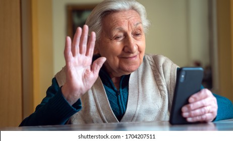 Authentische Aufnahme einer glücklichen Großmutter macht einen Selbstgespräch oder einen Videoanruf für Verwandte mit einem Smartphone zu Hause. Konzept der Technologie, der modernen Generation, der Familie, der Verbindung, der Authentizität