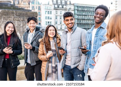 Authentic shot of happy group of multiracial friends millennials and generation z people in the city using mobile phones and laughing together - Friendship and lifestyle concepts - Shutterstock ID 2107153184